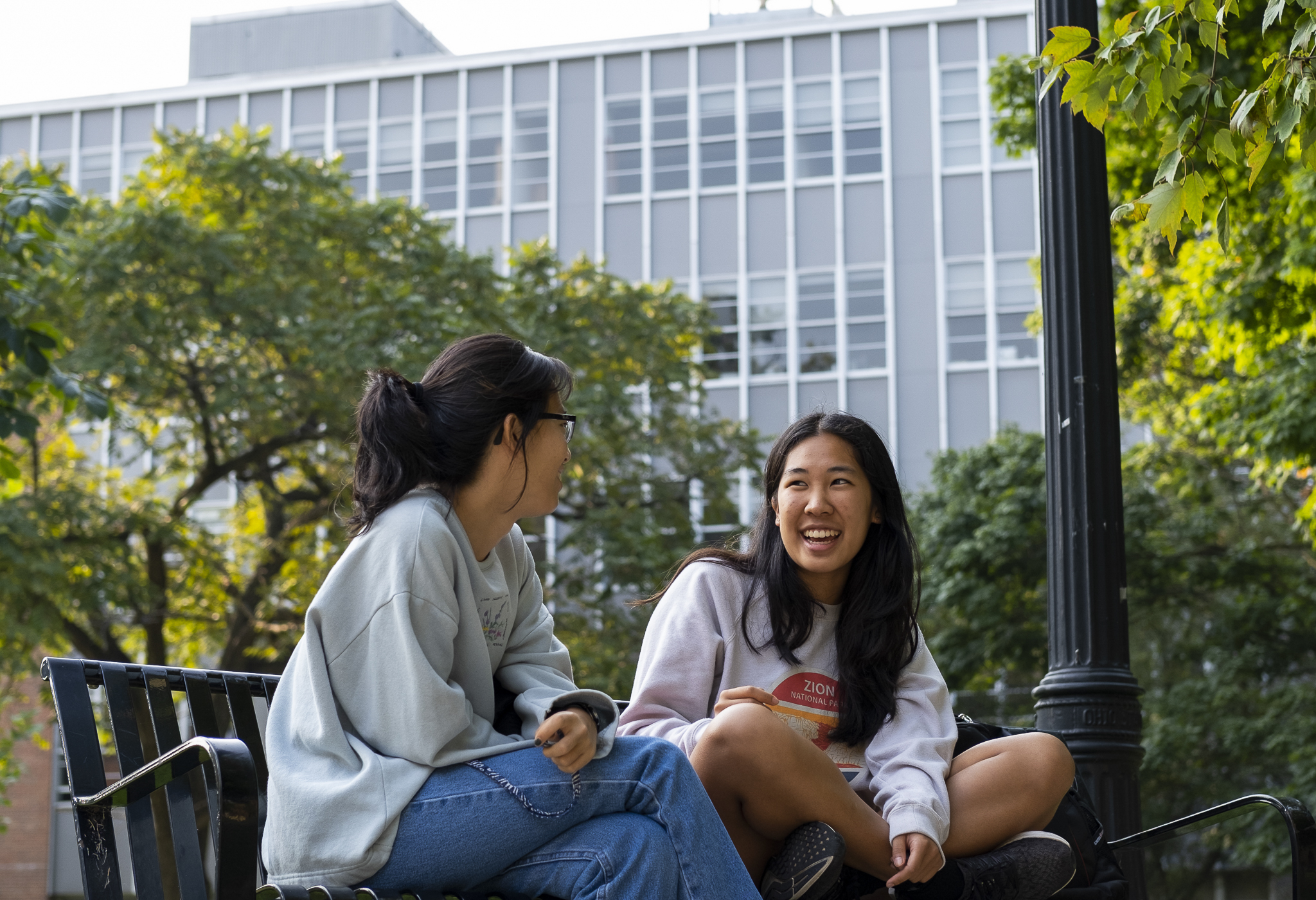 Students outside of Denney Hall on a bench. 