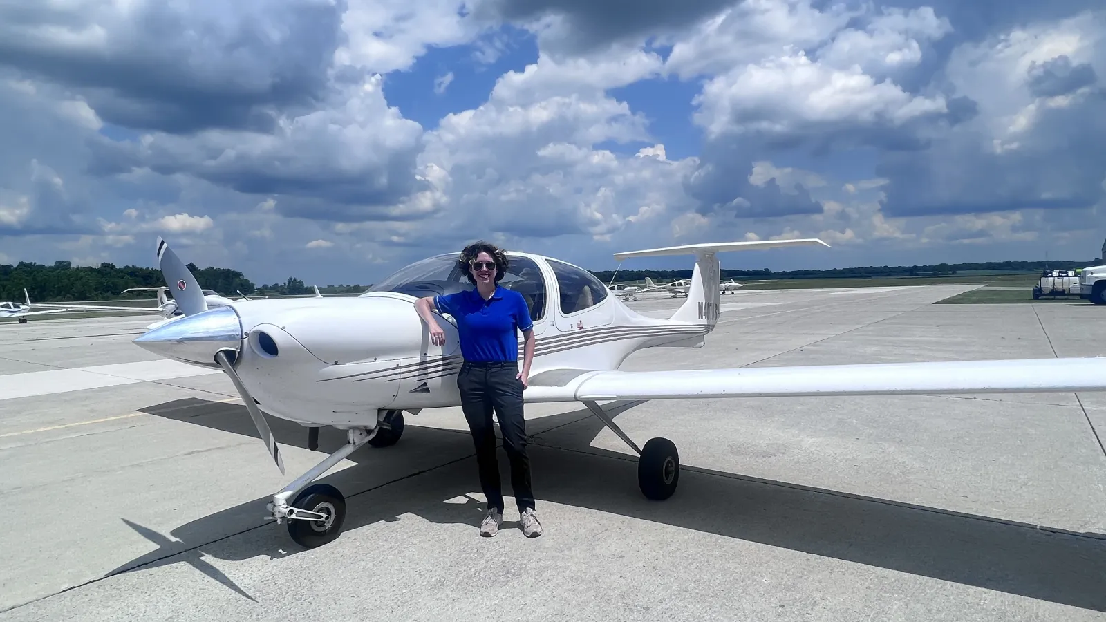 Bryn Barr standing next to a small prop plane. 