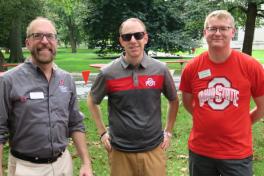 Two Ohio State employees stand with an alumni on the Oval