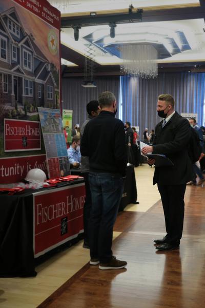 A student prepares to hand his resume to two employers during the 2022 Spring Career Fair.