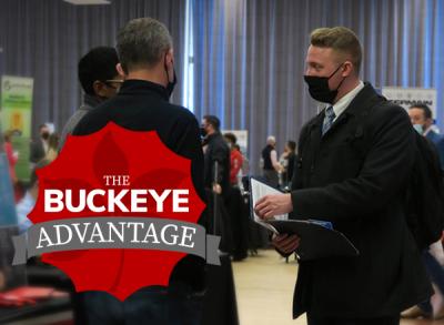 A student prepares to hand his resume to two employers during the 2022 Spring Career Fair.