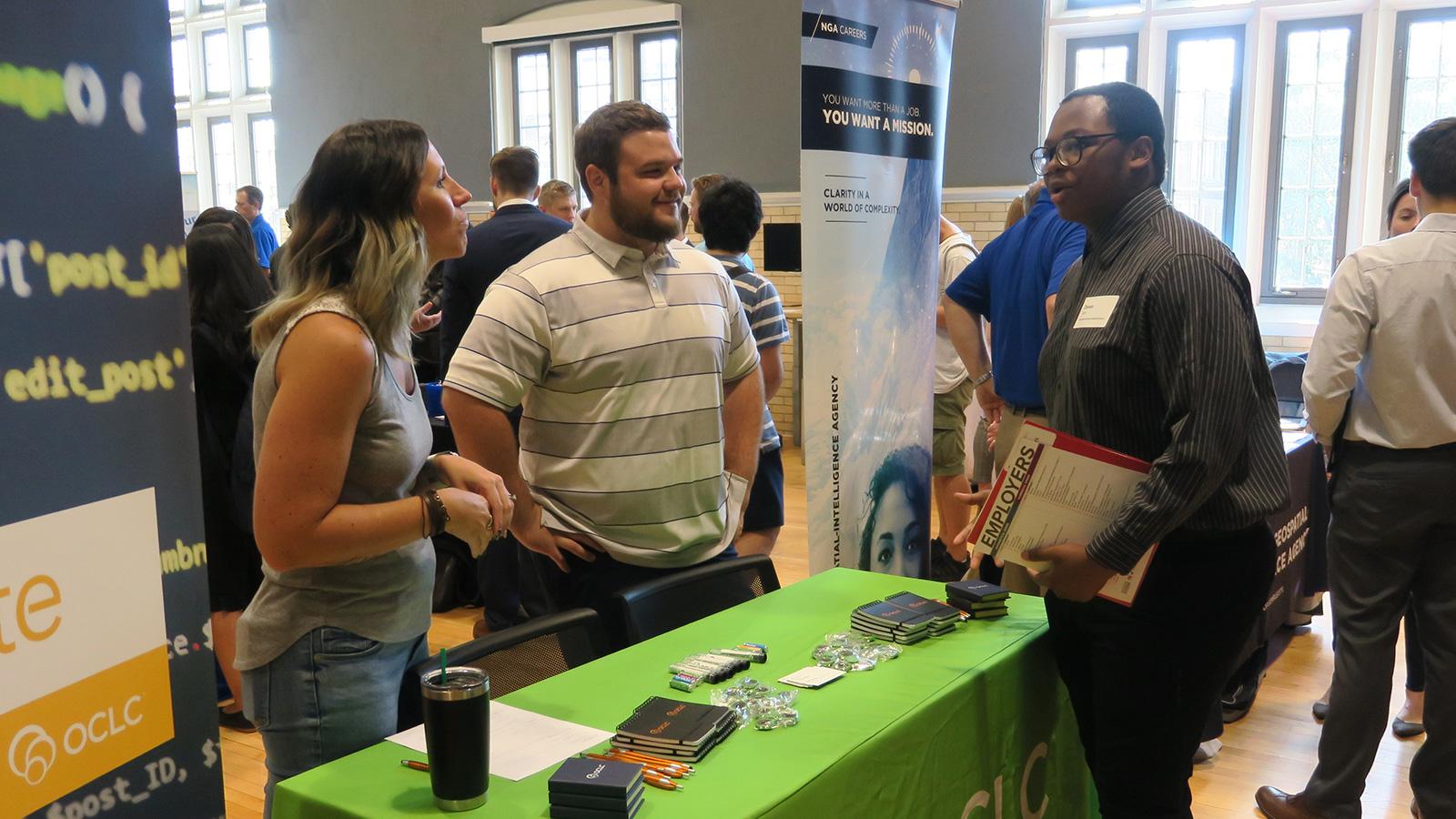 A student talks with two recruiters at the Technology and Data Analytics Career Expo